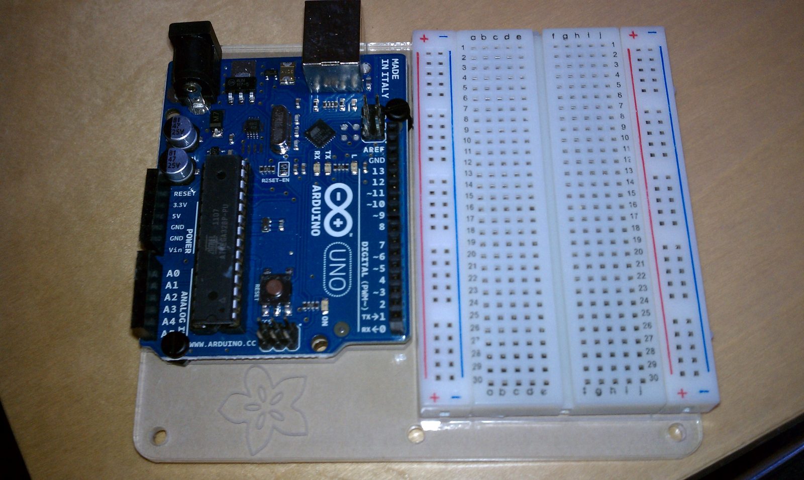 An Arduino Uno and an empty solderless breadboard mounted together on a base